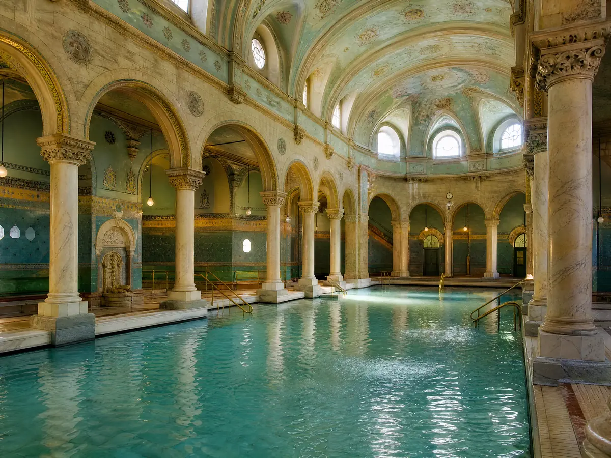 Una sala termale interna con archi, colonne e piscine calde, vuota